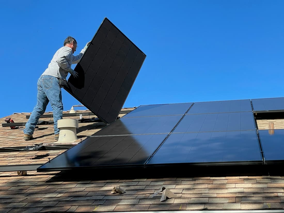 Certified installer fitting a solar panel and its wiring on a roof